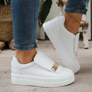 Detail view of stylish white platform sneakers with gold metal buckle and thick sole