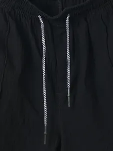Detailed view of black linen shorts featuring elastic waistband and patterned drawstring.
