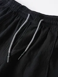 Close-up of black linen shorts featuring elastic waistband and patterned drawstring detail