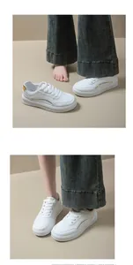 Détail de baskets blanches à plateforme avec touches dorées portées avec un jean