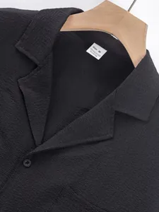 Close-up of black textured shirt fabric showing collar detail and size M label