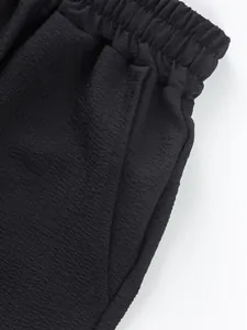 Close-up detail of men's black casual shorts showing elastic waistband and pocket