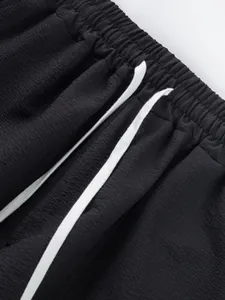 Detailed view of black elastic waistband with white drawstring on textured shorts