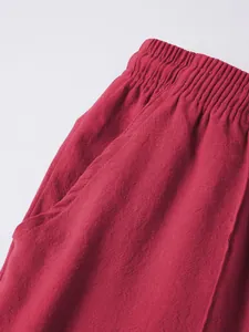 Detail shot of men's red linen beach shorts featuring elastic waist and side pocket texture.