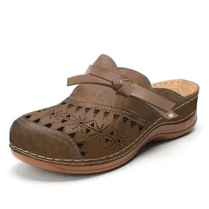Seitenansicht von braunen Keilclogs mit floralem Lasermuster und Schleifendetail