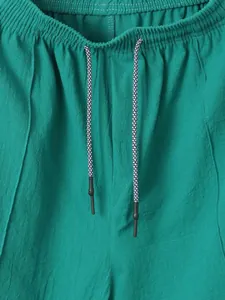 Close-up of green men's linen shorts showing elastic waistband and patterned drawstring detail