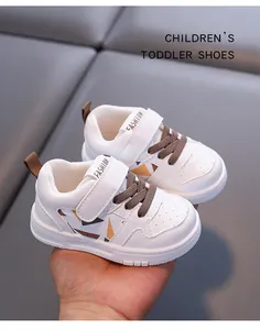 Primo piano di scarpe bianche per bambini piccoli con lacci marroni e motivi geometrici