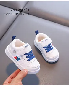 Primo piano di scarpe sportive bianche per bambini piccoli con lacci blu e velcro.