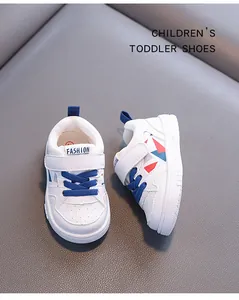 Dettaglio di sneaker bianche per bambini con lacci blu e dettagli geometrici.