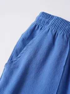 Detailed close-up of blue linen beach shorts showing elastic waistband and pocket