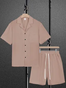 Close-up detail view of men's dusty pink short sleeve shirt and shorts set on hangers.