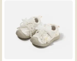 Close-up detail of toddler girl's cream walking shoes with pearls and mesh bows decoration
