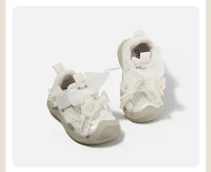 White ballet style baby girl walking shoes featuring delicate lace bows and pearl beads