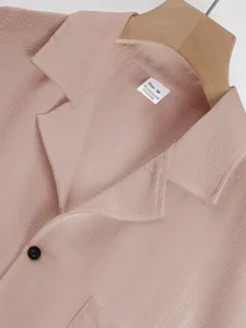 Detailed view of dusty pink textured shirt collar with black button and size tag.