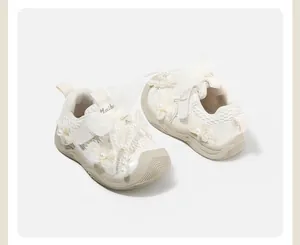 Detail of cream baby girl ballet-style sneakers with decorative pearls and lace
