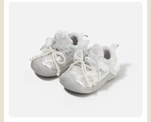 Close-up of silver baby girl sneakers with decorative pearls and mesh details.