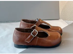 Detailweergave van bruine T-strap Mary Jane schoenen voor meisjes met zilveren gesp