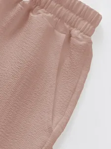 Close-up detail of elastic waistband and side pocket on textured dusty rose men's shorts