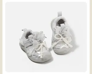 Detailed close-up of silver ballet-style baby girl sneakers with white pearl bows