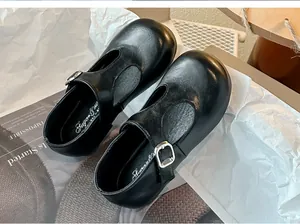 Detailopname van zwarte T-strap Mary Jane schoenen voor meisjes met een zilveren gesp
