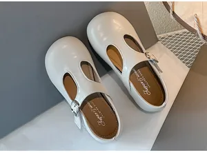 Detail van witte T-strap Mary Jane schoenen voor meisjes met zilveren gesp en zachte zool