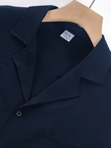Close-up detail of navy blue crinkle fabric texture and collar with Size M label