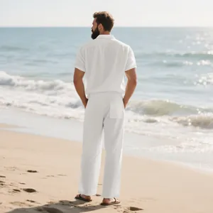 Vista trasera de un hombre con un conjunto de camisa y pantalón de lino blanco en la playa.