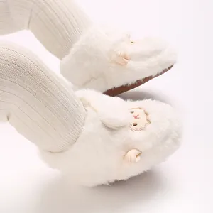 Gros plan de bottines bébé en peluche blanche avec un adorable motif de mouton brodé