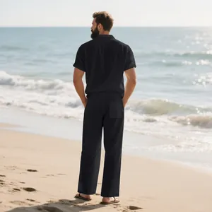 Vista trasera de un hombre con un conjunto de playa de lino negro en la orilla del mar