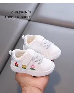 Detailaufnahme weißer Lauflernschuhe mit bunter Blumenstickerei und Klettverschluss.