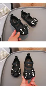 Visuale dettagliata di scarpe Mary Jane nere da bambina con fiocco e perle decorative