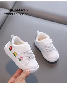 Detailansicht weißer Kleinkinderschuhe mit bunten Blumenstickereien und Klettverschluss