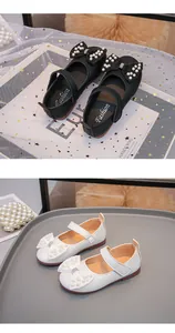 Dettaglio di scarpe da principessa in pelle per bambina, nere e bianche, con fiocchi di perle