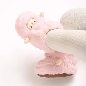 Gros plan de jolis bottines de bébé en peluche rose avec motif mouton et leggings.