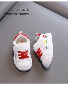 Detailansicht weißer Lauflernschuhe für Kleinkinder mit Blumenstickerei und roten Schnürsenkeln