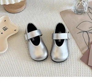 Detailed view of shiny silver girls Mary Jane shoes with buckle strap on textured fabric.