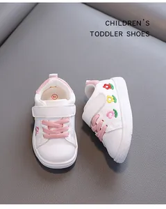 Nahaufnahme weißer Kleinkinderschuhe mit Blumenstickerei und rosa Klettverschluss
