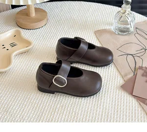 Close-up of brown Mary Jane children's shoes with silver buckle and matte leather