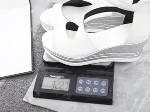 Weiße Keilsandale mit einem Gewicht von 322,7 Gramm auf einer digitalen Präzisionswaage