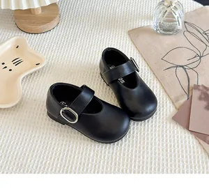 Detail view of black girl's Mary Jane shoes with silver buckle on a textured background
