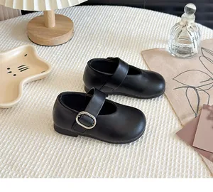 Detail view of black Mary Jane shoes for girls with silver buckle on a cozy background.