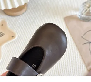 Detailed view of high-quality brown leather texture on stylish girl's Mary Jane shoe