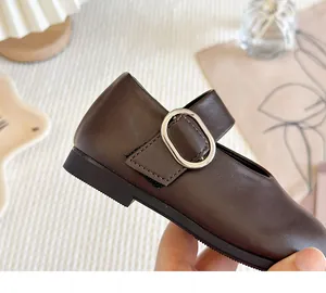 Detailed close-up of brown girls Mary Jane leather shoes featuring a silver metal buckle