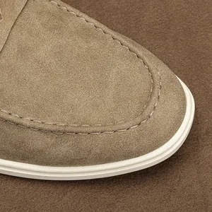 Detailed view of fine stitching on a premium tan suede loafer with a clean white sole.