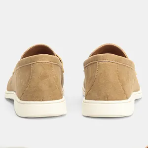 Rear view detail of minimalist men's suede slip-on loafers in camel color with white soles.