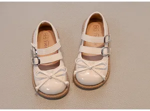 Top view detail of elegant cream patent leather girl's Mary Jane shoes with bow and straps