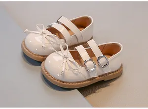 Close-up of cream patent leather Mary Jane shoes with bows and double buckles