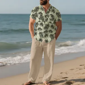 Vista detallada de un hombre con camisa estampada de palmeras y pantalón de lino en playa.