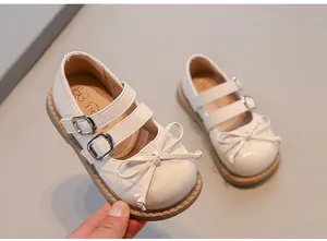 Detailed view of cream girls' Mary Jane princess shoes featuring double buckle straps and a bow