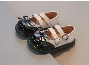 High-quality close-up of girls' black and cream two-tone Mary Jane shoes with bow detail